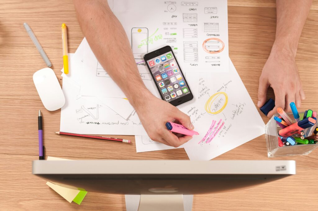 A desk with papers, pens and a desktop with someone brainstorming brand identity ideas.